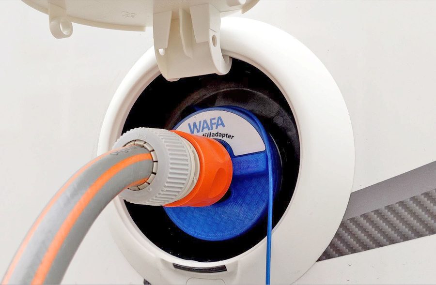 WAFA 4 im runden weißen Einfüllstutzen eines Wohnmobils, daran ein Schlauch mit orangefarbener Kupplung